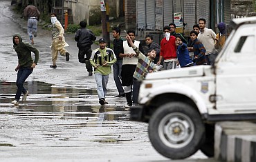 Protesters throw stones and pieces of bricks at an police vehicle in Srinagar