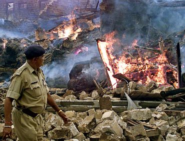 A policemen walks past a building which was burnt during the post Godhra riots in Gujarat