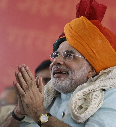 Modi wears an traditional Indian turban as he gestures to his supporters on second day of his fast
