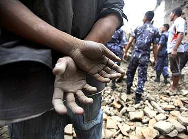 The hands of a resident are seen covered with mud as rescuers search for casualties in the ruins of a quake-damaged house at Lokanthali in Bhaktapur