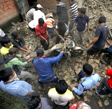 Residents remove a motorbike that was buried in the ruins of a quake-damaged house at Lokanthali in Bhaktapur