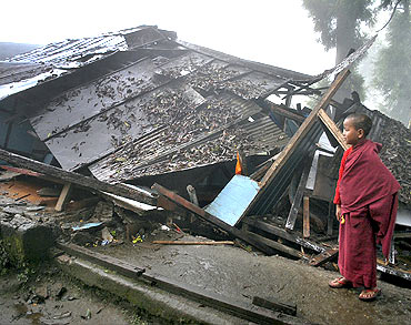 A monk looks over a damaged house in Gangtok