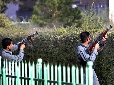 Afghan policemen fire toward a building which the Taliban insurgents took over during an attack