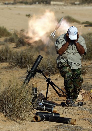 An anti-Gaddafi fighter fires a mortar against loyalists near Sirte