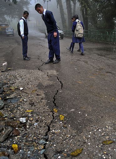 Schoolboys stop to look at a crack running down a road following the earthquake in Gangtok