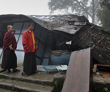 Young monks walk past a damaged house after the earthquake in Gangtok