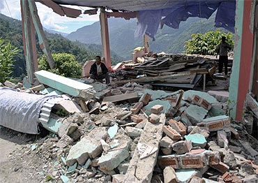 A man sits amid the rubble of a building which was destroyed by Sunday's earthquake at Rangrang village