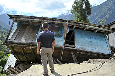 A man stands in front of his house, which was damaged by Sunday's earthquake, at Mangan village