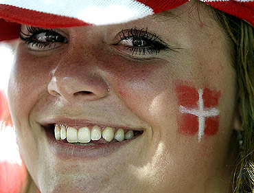 A Danish fan with a painted face smiles before a match