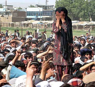An Afghan girl whose family members were killed overnight after a raid by NATO and Afghan forces, covers her face as she weeps during a protest in Taloqan