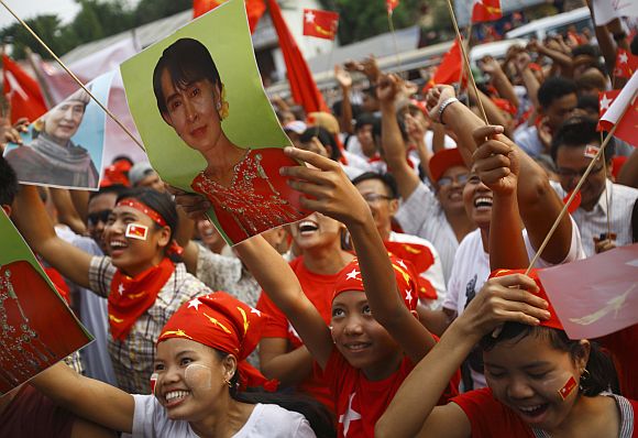 Supporters of the NLD party cheer as they watch increasing votes on a screen at the roof of the NLD office in Yangon