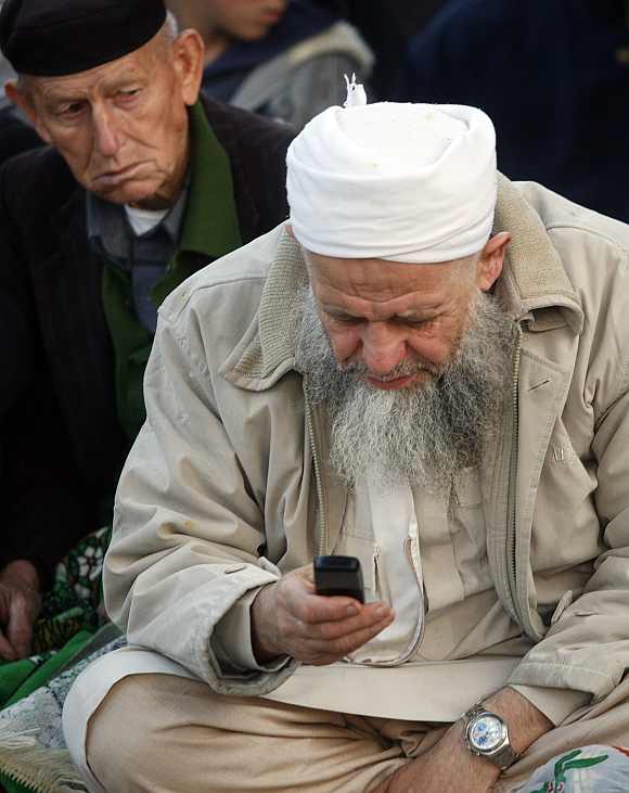 A man looks at a mobile phone as he attends special prayers