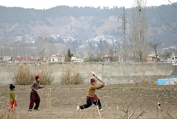 Children play cricket near the boundary wall of the building where Al Qaeda leader Osama bin Laden was killed