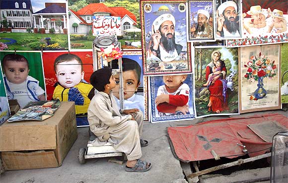 A child looks up at posters depicting slain Al Qaeda leader Osama bin Laden at a roadside stall in Quetta