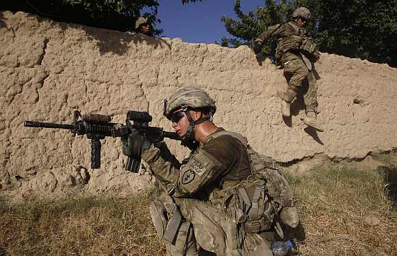 US army soldiers from Charlie company 4th platoon,1st brigade 3-21 infantry, jump over a wall during a patrol in the village of Chariagen in the Panjwai district of Kandahar province southern Afghanistan