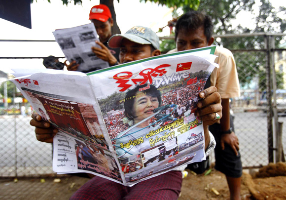 People on a walkway in Yangon read a newspaper announcing Suu Kyi's victory