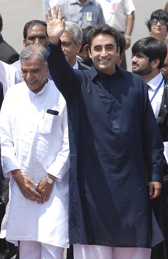 Bilawal Bhutto Zardari waves upon their arrival while Parliamentary Affairs Minister Pawan Kumar Bansal looks on at the airport in New Delhi
