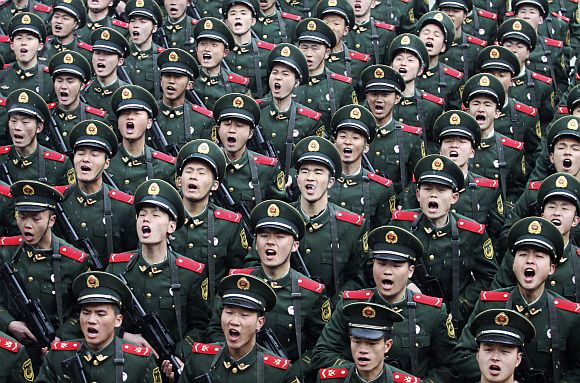 Recruits of the Chinese Army shout slogans during a handover ceremony on a rainy day at a military base in Hangzhou