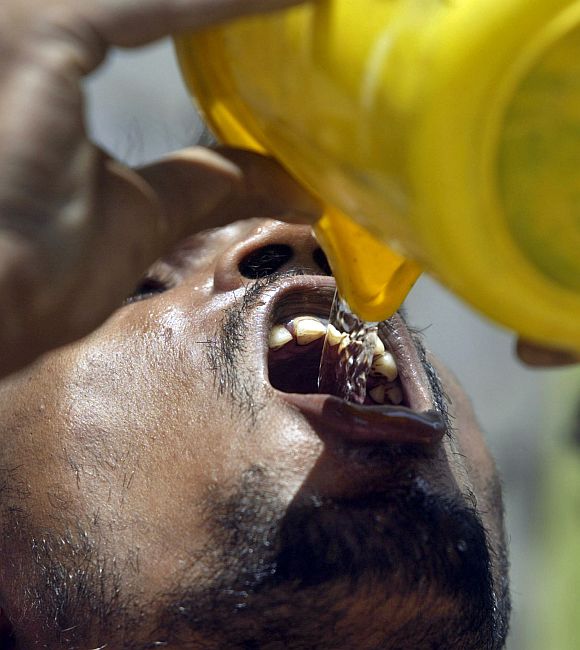 A labourer drinks water as he works at construction site in Allahabad
