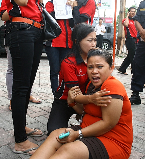 Office workers panic as they evacuate and gather in front an office building in Medan after the quake.