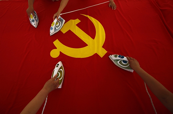 Workers use electric irons to smooth out a Communist Party of China flag on a table at the Beijing Jingong Red Flag factory, located on the outskirts of Beijing