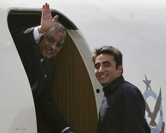Pakistan's President Zardari waves as his son Bilawal looks on before they depart for Jaipur at the airport in New Delhi on April 8