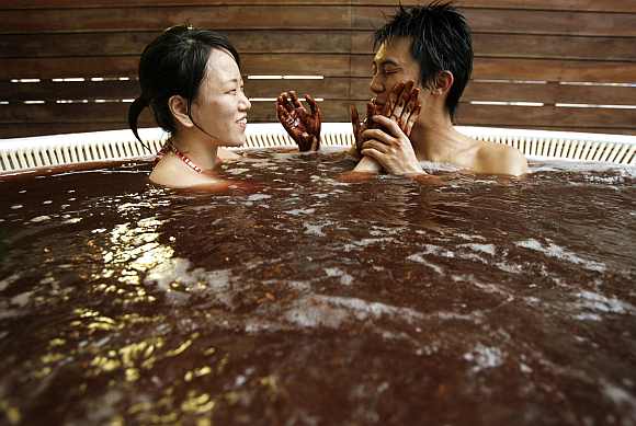 A woman spreads chocolate on her boyfriend's face in a bath incorporating chocolate at a hot springs spa resort in Hakone, west of Tokyo
