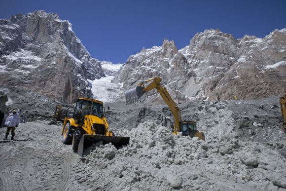 Pakistani soldiers use heavy machinery to dig through the snow at the site of an avalanche in Gyari