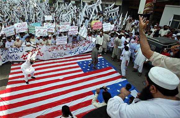 A supporter of the Jamaat-ud-Dawa Islamic organisation beats the US flag with his shoes during an anti-American rally in Karachi