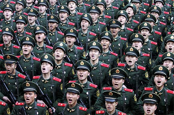 Recruits of the People's Liberation Army shout slogans during a handover ceremony on a rainy day at a military base in Hangzhou, Zhejiang province