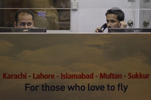 Bhoja Air employees sit behind computers in a ticket booth at the Jinnah International Airport in Karachi