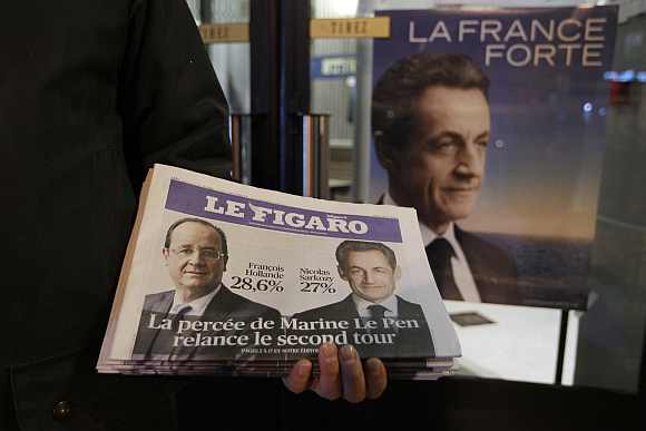 A newspaper hawker displays an early edition of Le Figaro outside the Mutualite meeting hall in Paris after the first round of the 2012 French presidential election
