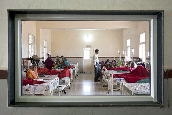 Women who have recently given birth and their relatives are pictured through a nurse's observaton window