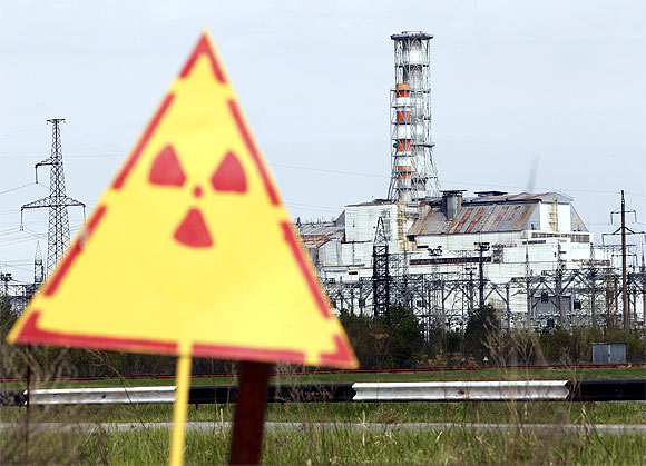 A hazard sign indicating radiation is seen in front of a containment shelter for the damaged fourth reactor at the Chernobyl nuclear power plant
