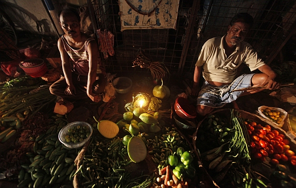 Vegetable vendors wait for customers at their stall during a power-cut in Kolkata