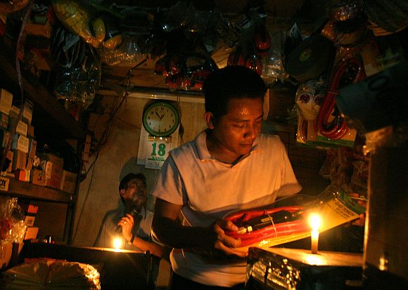 Merchants work with the help of candles at a market in Jakarta's China town August 18, 2005