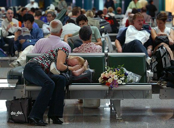 A woman sleeps on her luggage as she waits at Rome's Fiumicino airport September 28, 2003