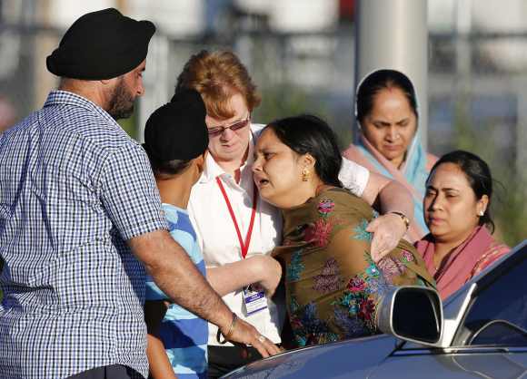 A distraught women is helped to a car outside of the Sikh temple in Oak Creek