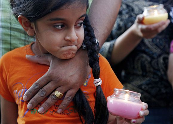 Bani Kaur holds a candle as she stands with her father Manjeet Kaur during a candle light vigil for victims of a shooting at a Sikh temple, at Cathedral Square in downtown Milwaukee