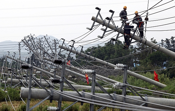 Labourers work to reconnect an electric circuit after pylons were turned over by Typhoon Haikui in Wenling, Zhejiang province