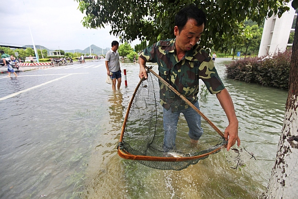 A man fishes on a flooded street after Typhoon Haikui hit Taizhou, Zhejiang province