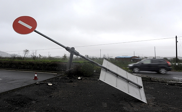 A car drives past a damaged traffic sign as Typhoon Haikui hits Hepu township, Zhejiang province