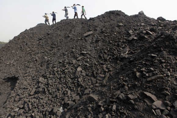 Workers walk on a heap of coal at a stockyard of an underground coal mine in Odisha
