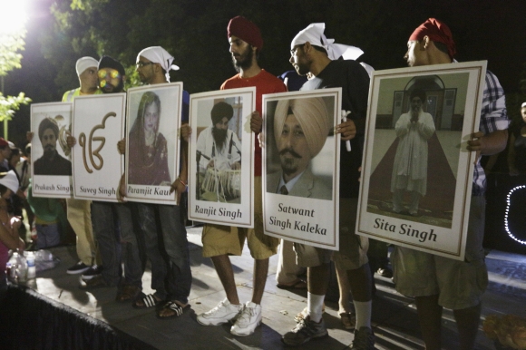 Sikhs hold up placards with photos of six mass shooting victims after a candlelight vigil in Oak Creek, Wisconsin
