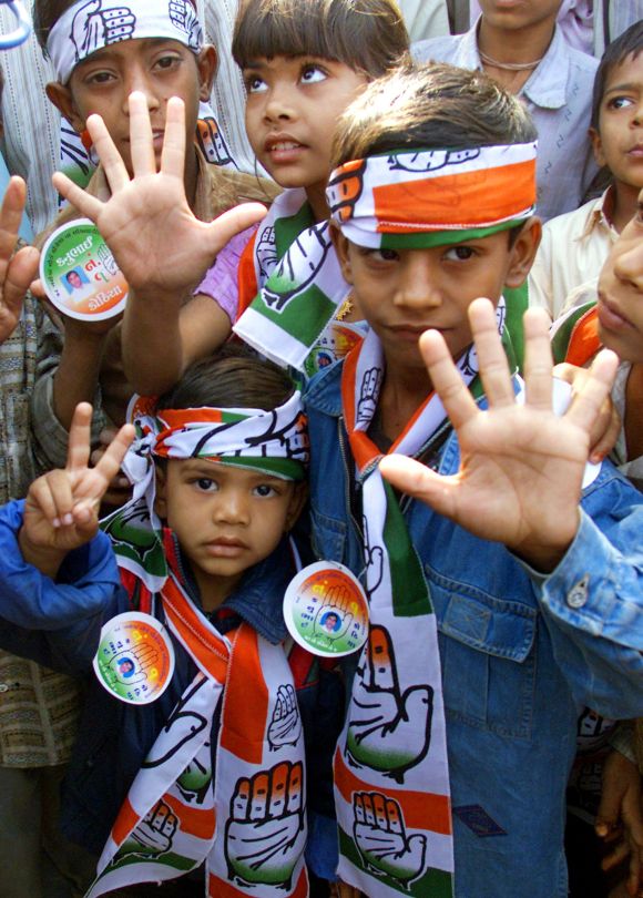 Children display campaign material of the Congress party near a polling booth in Gujarat