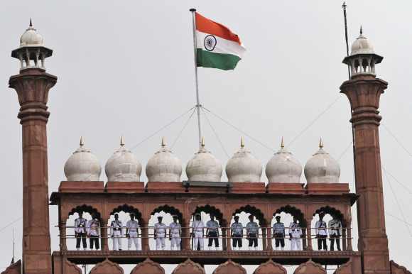 Buglers from the armed forces stand on the balcony of the historic Red Fort as the national flag flutters during the full-dress rehearsal for Independence Day celebrations