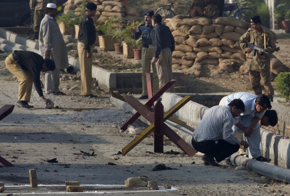 Security forces survey the site of a suicide bomb attack at the entrance of the Pakistan Aeronautical Complex in Kamra