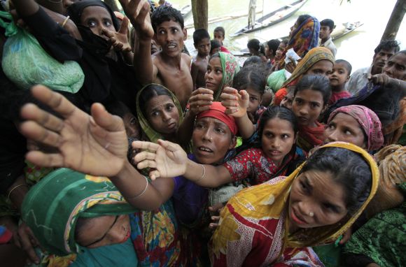 People wait for food to be distributed by local organisations as they take shelter at a school building in flood-hit Sylhet in Bangladesh on June 30, 2012