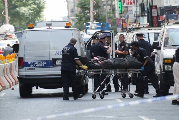 The body of a shooting victim is moved by the New York City Coroner near the site of the Empire State building where a gunman opened fire shooting several bystanders before being killed by police