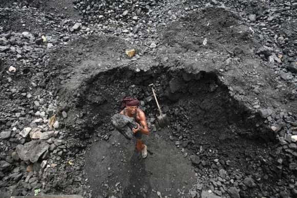 A labourer loads coal onto a truck at a coal yard on the outskirts of Jammu